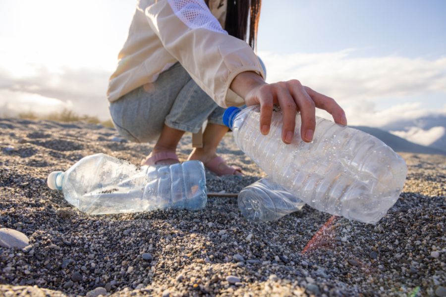 person picks up plastic littered on the beach