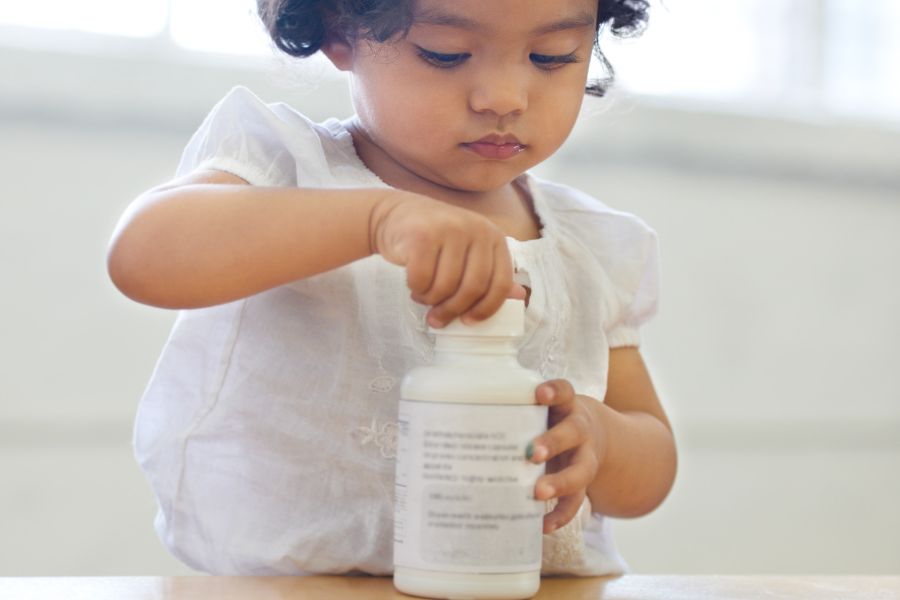 child tries to open a medication bottle with child-resistant cap