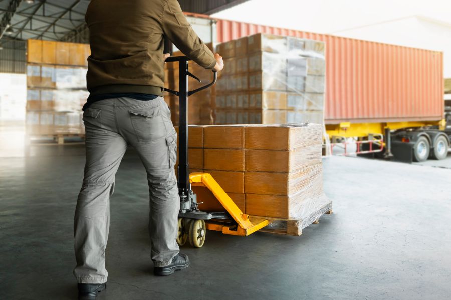 Person loading a pallet of products onto a truck.