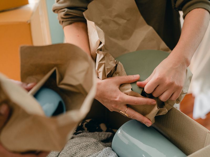 business owner wraps kraft paper around products to secure for safe packaging and shipping