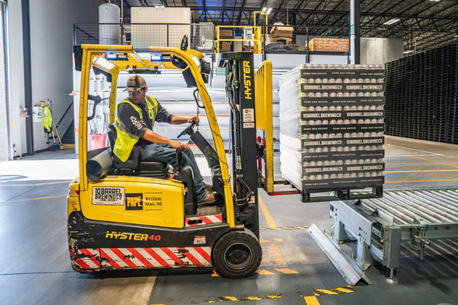 Forklift operator moving pallets of wholesale packaging onto container.