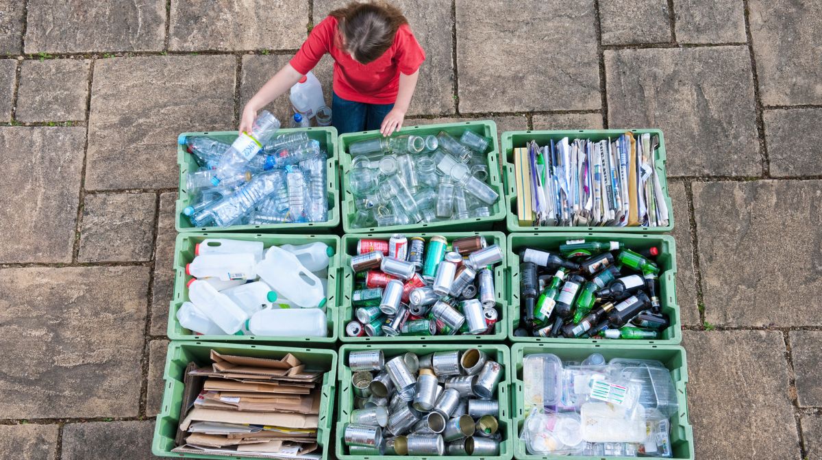 Person sorting recyclable materials into recycling bins