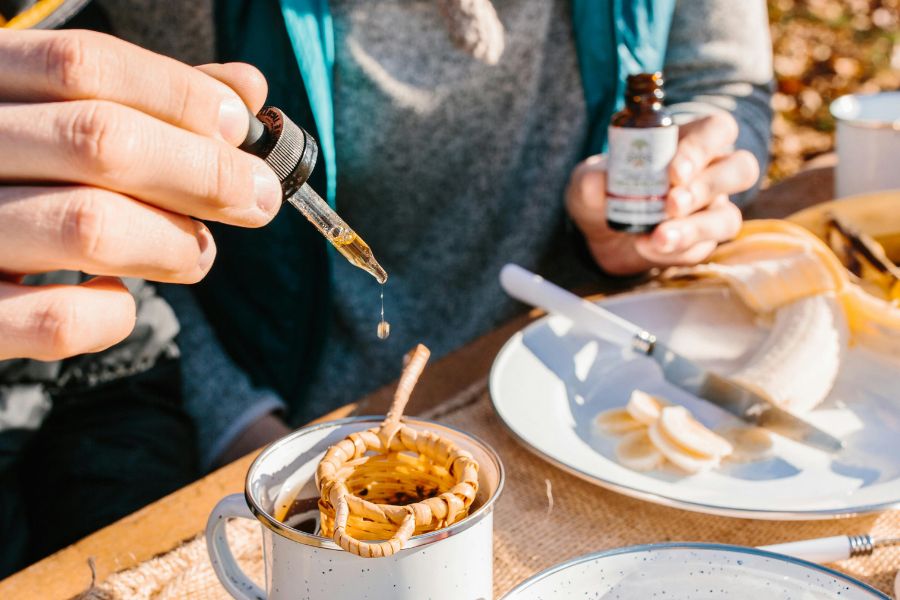 Person adds liquid supplement to tea using a dropper 