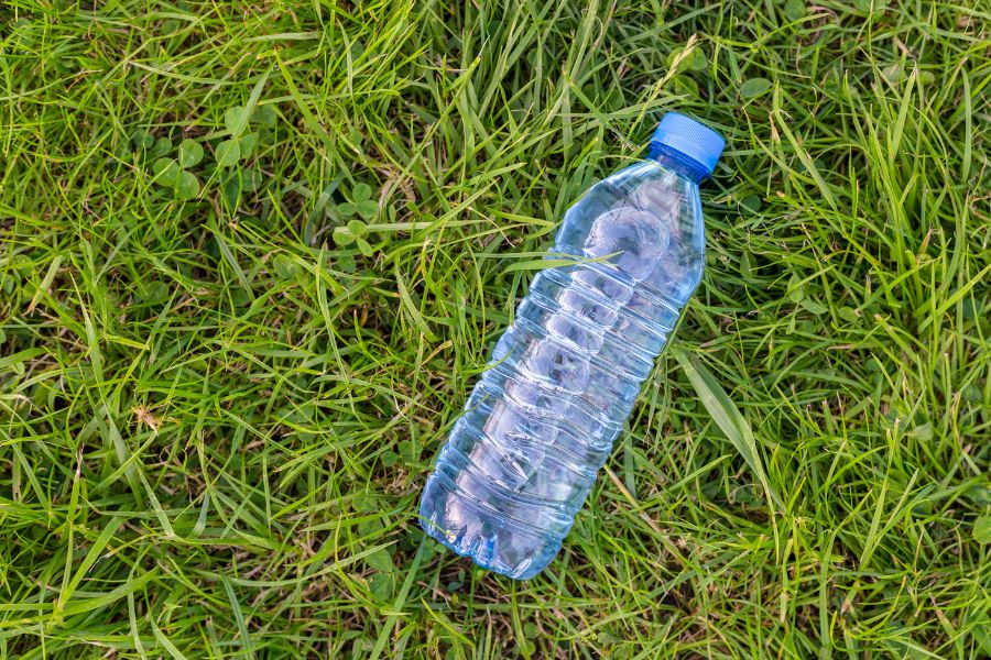 Clear recyclable plastic water bottle made from recycled material laying on the grass