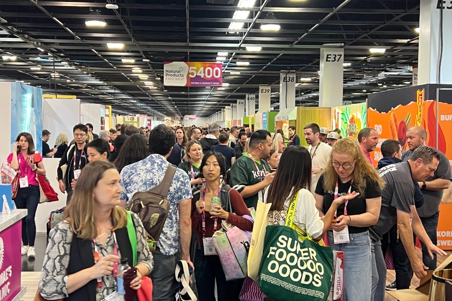 Bustling expo hall with an aisle crammed full with attendees