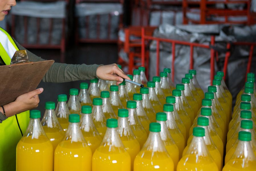 Warehouse worker counts beverage bottle inventory on a pallet